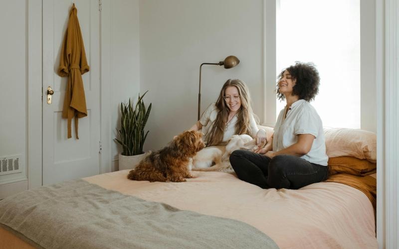 two women and a dog sitting on a modern bed